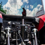Male mechanic checking farm tractor using digital tablet in rural area
