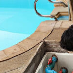 Technician fixing swimming pool water pump. Service and maintenance for swimming pool.